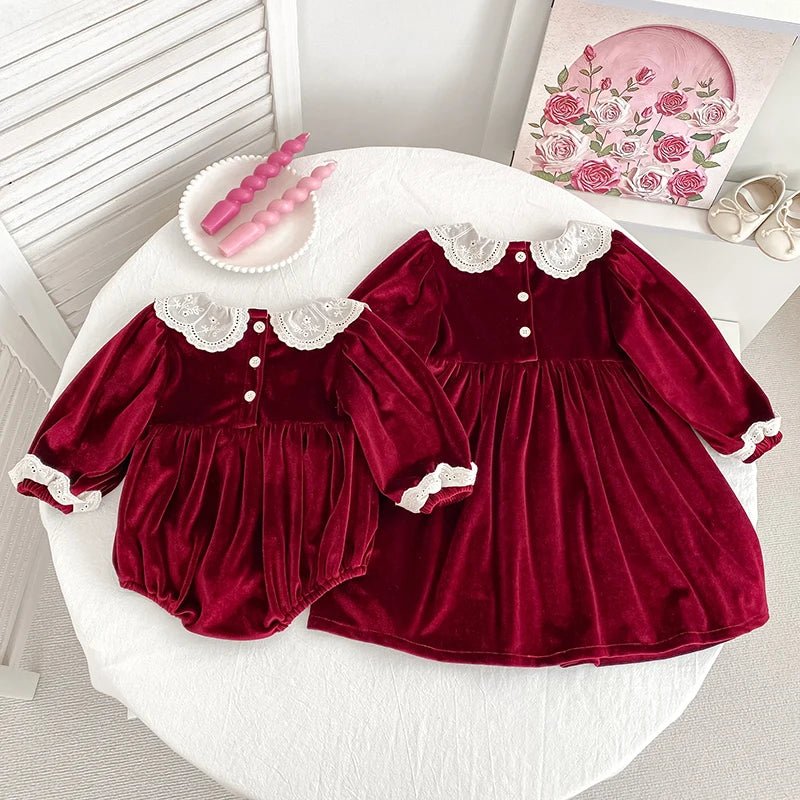 Deck the Halls Smocked Velvet and Frills Sibling Outfits in Deep Red - Beautiful siblings' outfits displayed on a table with floral accents.