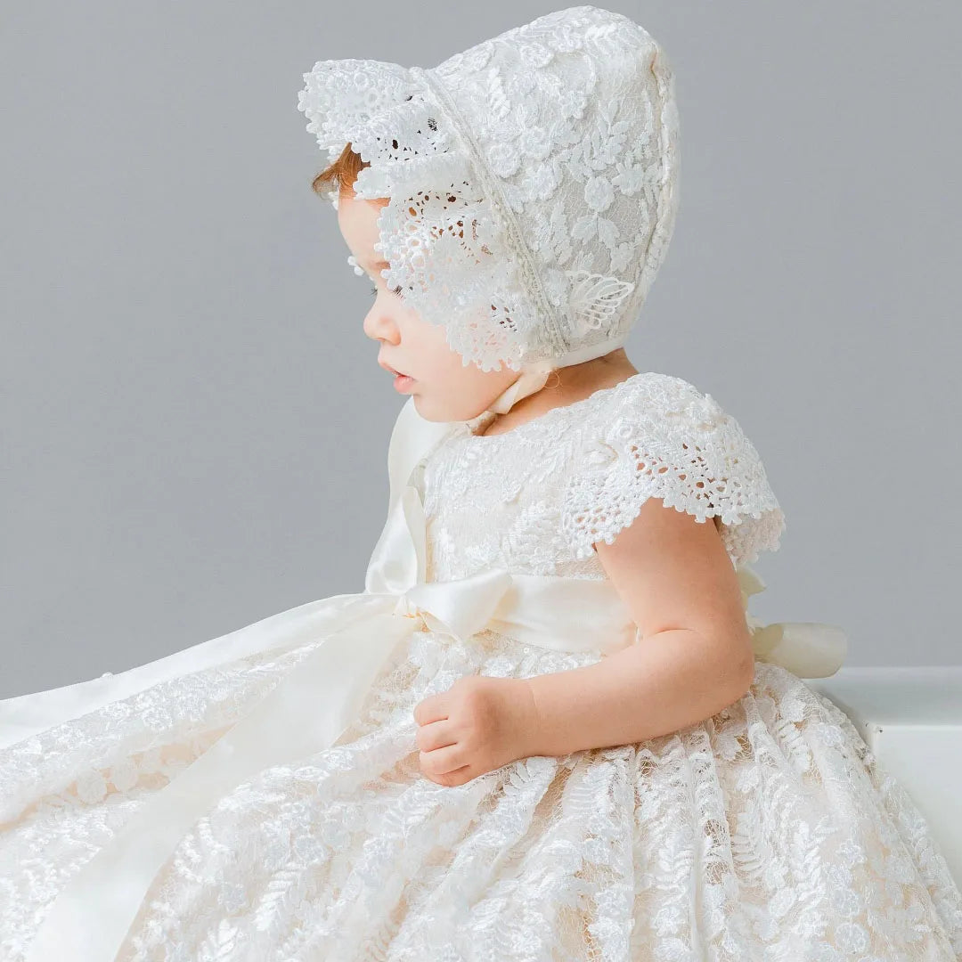 Elegant ivory lace gown and matching bonnet set for infants. Features satin bow and floral appliques, perfect for baptism, weddings, and special occasions.