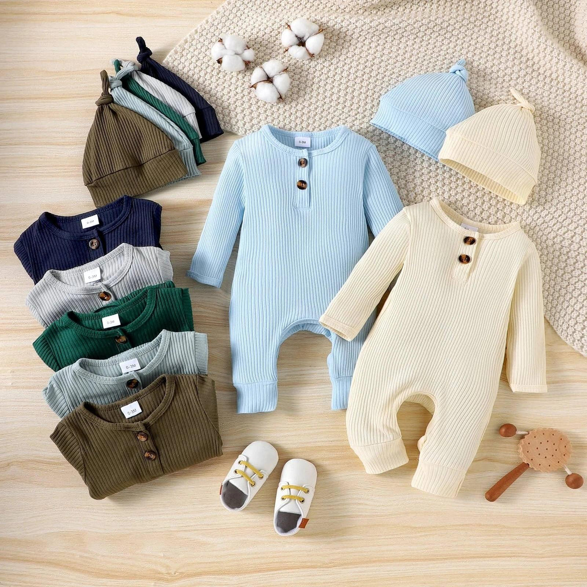 Light blue and cream ribbed romper sets for babies with matching hats and shoes laid out flat