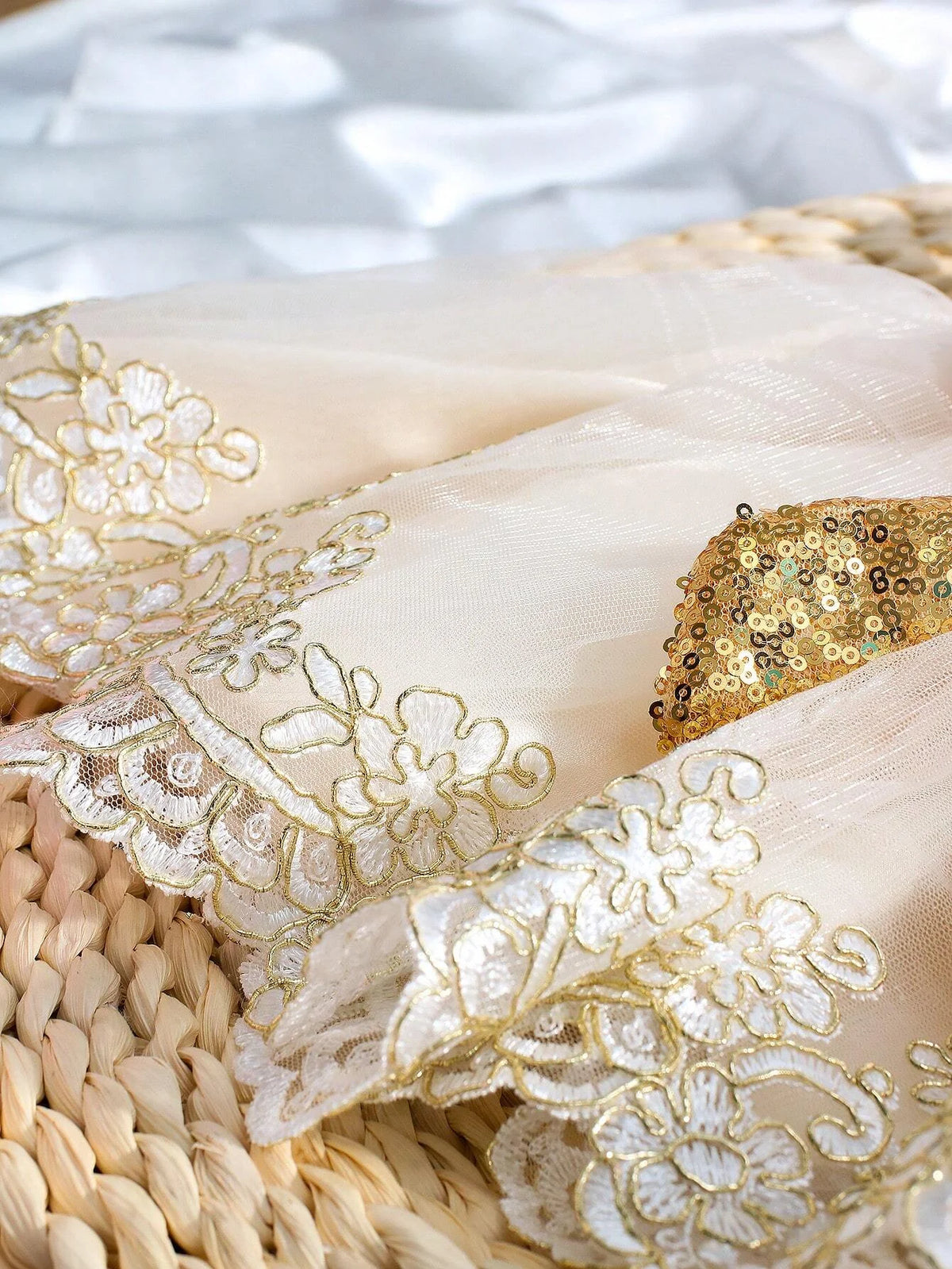Ivory infant gown fabric with gold sequined bow and floral embroidered lace edges.