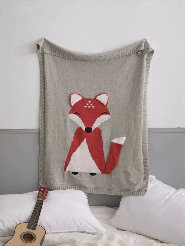 An adorable gray fox blanket displayed on a bed, featuring designs from the 'Sleepy Tight' cute animal blankets for kids.