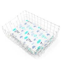 Two-layer bamboo cotton baby swaddle blanket displayed in a white wire basket with blue cloud and raindrop pattern.