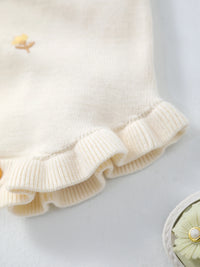 Cream knit romper with frilly cuffs and crocheted yellow floral detail; for babies to 18 months.