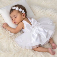 Lara Elegant infant dress with a large back bow, tulle overskirt, and matching beaded headband in white.