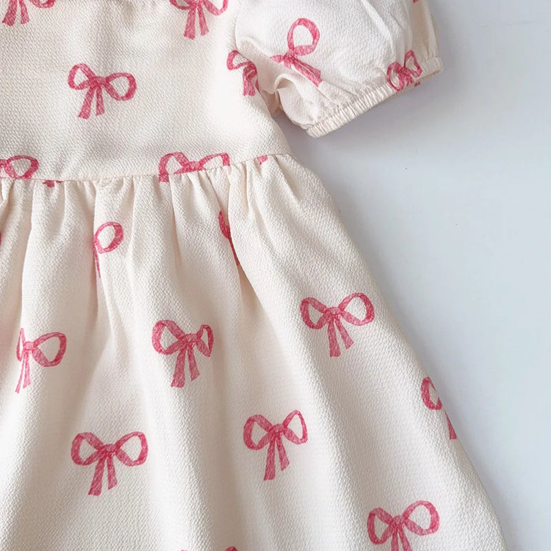 Detailed view of the flared skirt of the Sweet Little Bows Party Dress, emphasizing the cute pink bows and comfortable fit.