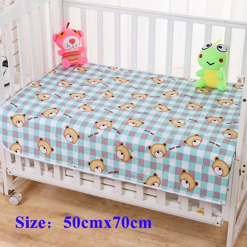 Waterproof changing pad cover with bear-face prints on blue-pink plaid, 50x70 cm, on a baby crib with plush toys.