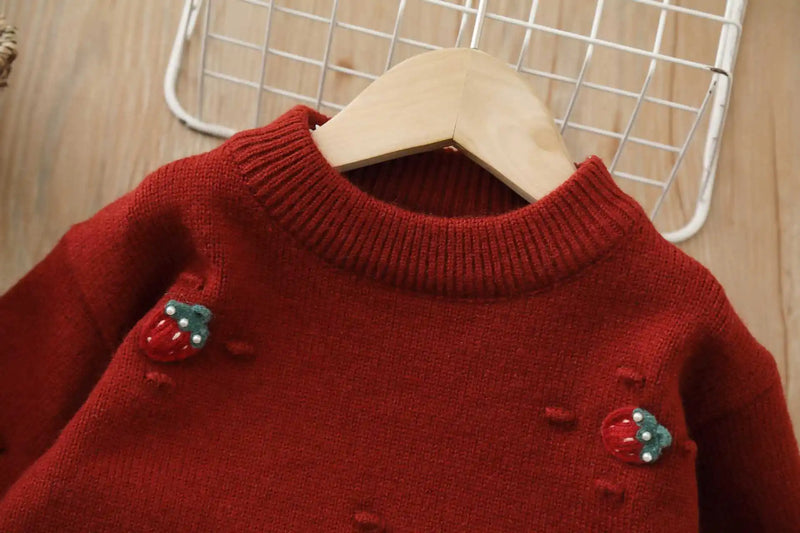 Close-up of the knit sweater from the Strawberry Girls Knit Sweater and Tulle Skirt - Deep Red, featuring 3-D strawberry embroidery and a cozy round neckline.
