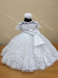 White lace flower girl dress with tiered tulle skirt, intricate appliques, and large back bow for weddings or special occasions.