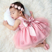 Lara Elegant pink infant dress with oversized satin bow, beaded headband and tulle overskirt for special occasions.