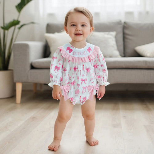 Child wearing a pink and white outfit with bows in a living room setting