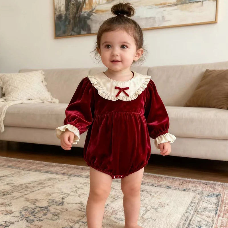 Charming little girl modeling the 'Frilly Crissy' Winter Velvet Bubble, showcasing soft velvet with frilled cuffs. A delightful baby bubble romper for festive occasions.