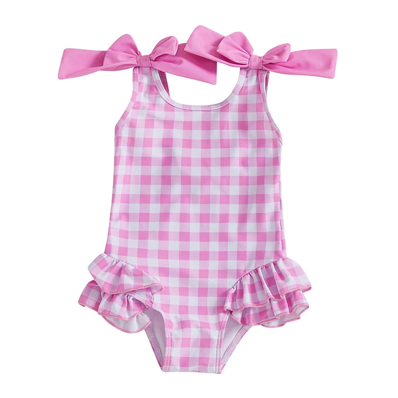 Cute In Checks cute swimsuit for kids in princess pink featuring playful bows and ruffles, ideal for summer fun.