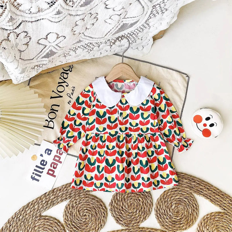 Red floral 'Mariella' Floral Print Peter Pan Collar Dress laid out on a decorative background, showcasing its elegant design and classic collar.