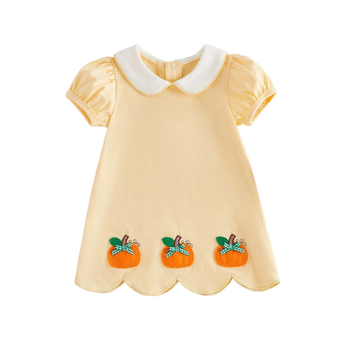A pale yellow baby dress with a white Peter Pan collar, short puff sleeves, and three orange pumpkin appliques with green plaid ribbons near the scalloped hem, shown on a plain white background.