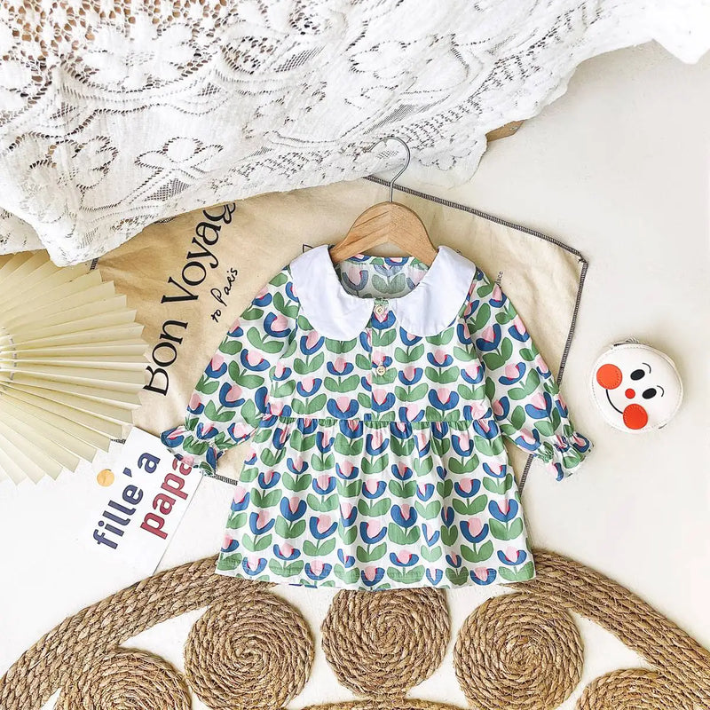 Green floral 'Mariella' Floral Print Peter Pan Collar Dress laid out on a decorative background, highlighting its charming patterns and Peter Pan collar.