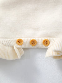 Cream knit baby cardigan with ribbed trim and three peach buttons.