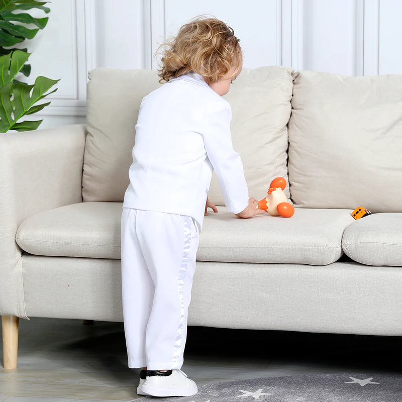 Back view of Hudson Boys' Tuxedo Set in white, showcasing a small boy playing while wearing the complete tuxedo ensemble.