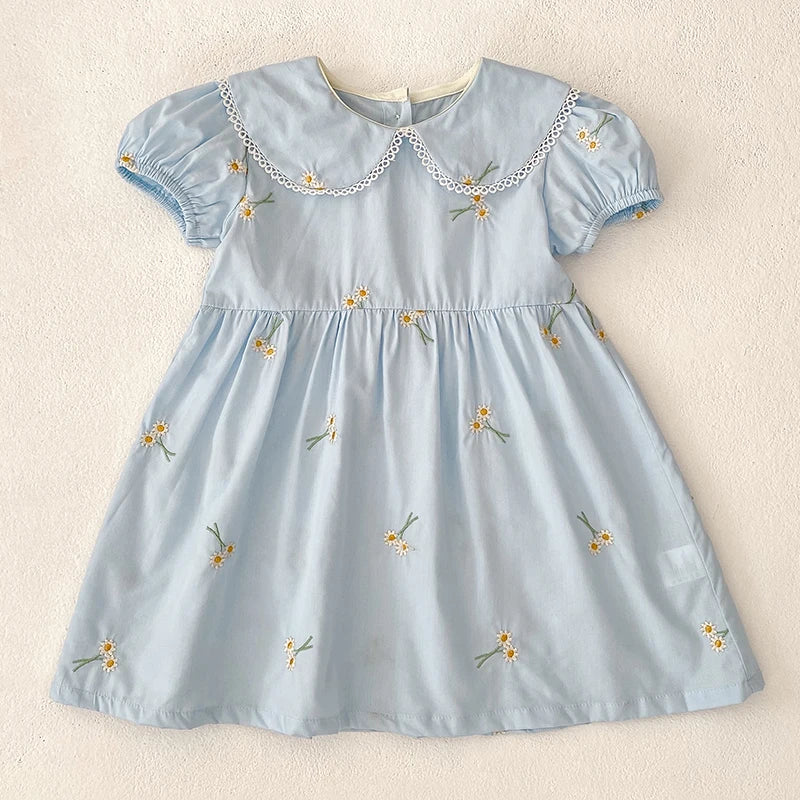 Sweet Lydia Little Girl's Dress in sky blue with delicate embroidered daisies and lace accents on the puff sleeves, perfect for playful events.