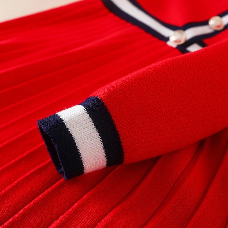 Close-up detail of the Preppy Darla Knit Dress Long Sleeves showcasing the red fabric and navy striped accents on the sleeve. Perfect for fashion-forward kids.