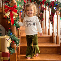 Toddler girl in white Merry Christmas pullover and green velvet bell-bottom flare pants on festive stairs.
