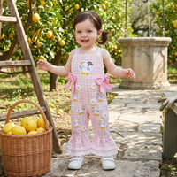 Child in a pink floral dress with bird designs standing in an orchard with lemons.