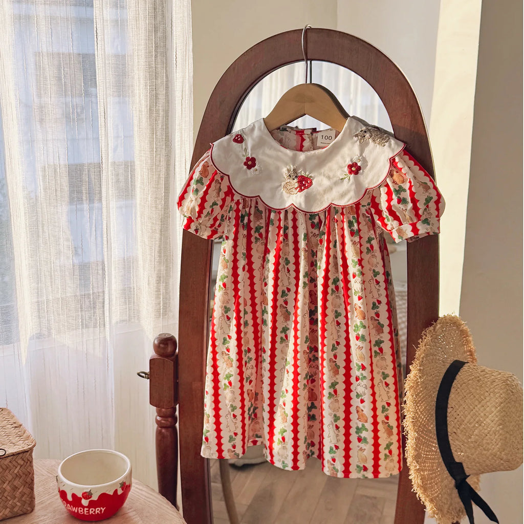Front view of the 'Constance-Marie' classic embroidered dress for girls, designed for ages 4-6 years, featuring vibrant strawberry prints and a Peter Pan collar, displayed in a stylish setting.