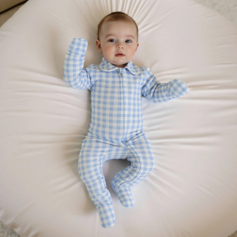 Baby in the 'Baily' Checked Footie in Boca Blue, posing playfully on a plush surface.