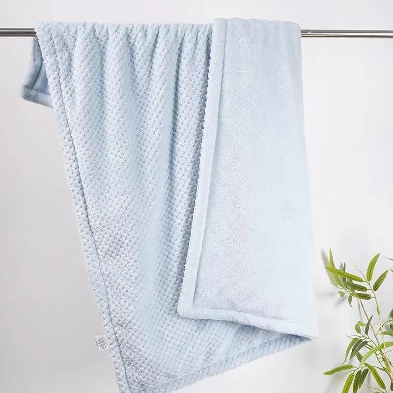 Two light-blue baby blankets, one smooth fleece and one waffle-knit, hanging on a rod.