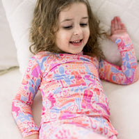 Girl in pastel cowgirl-themed Saddle Up Second-Skin 2-Piece Long Sleeve Pajama set for girls.