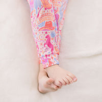 Child's legs in Saddle Up cowgirl pajama pants with pink pastel print.