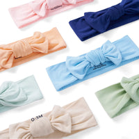 Flat-lay of seven soft bamboo rayon blend headbands in various colors arranged diagonally with care labels