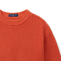 Angled view of rust-orange baby sweater shoulder seam and ribbed crew neck collar detail