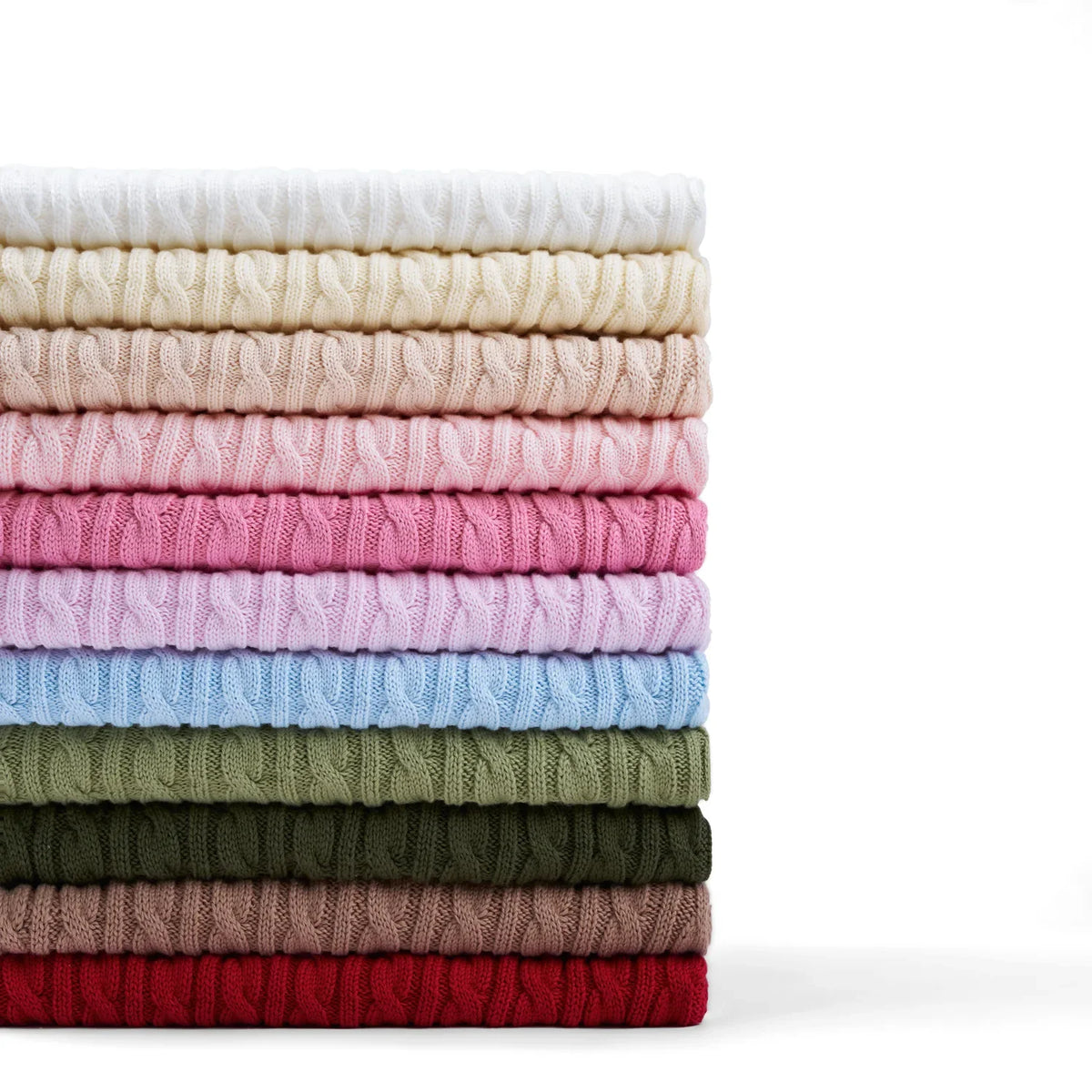 Vertical stack of eleven folded cable knit sweaters displaying color gradient from white to deep red