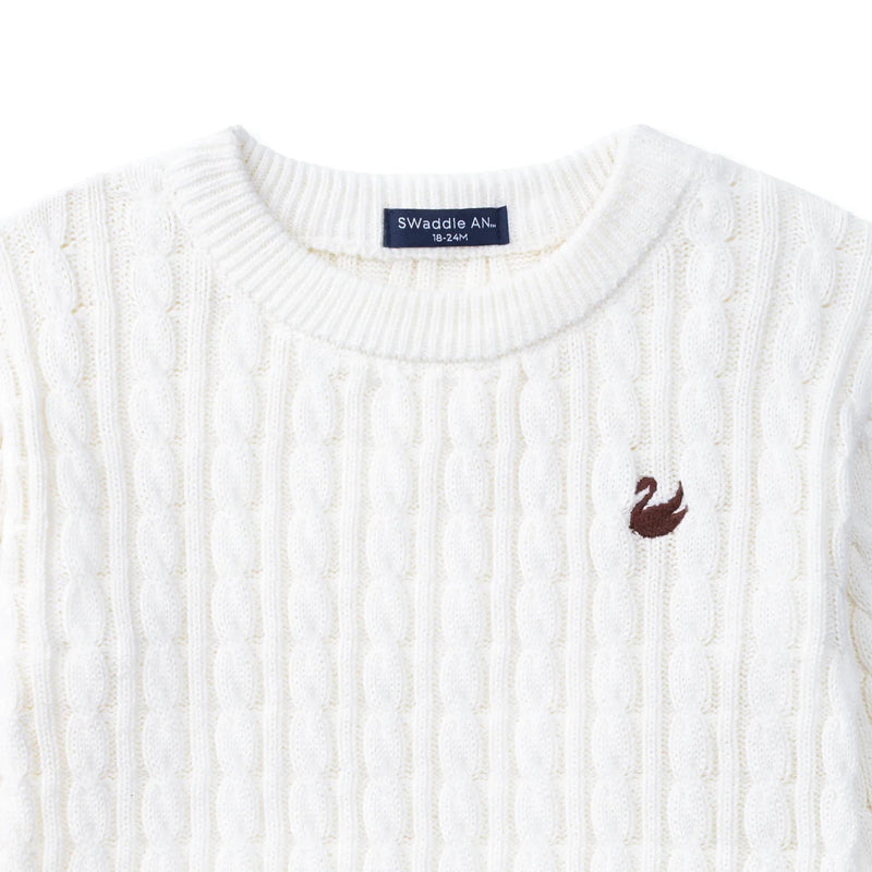 Close-up of white cable knit texture, navy size tag, and brown embroidered swan logo