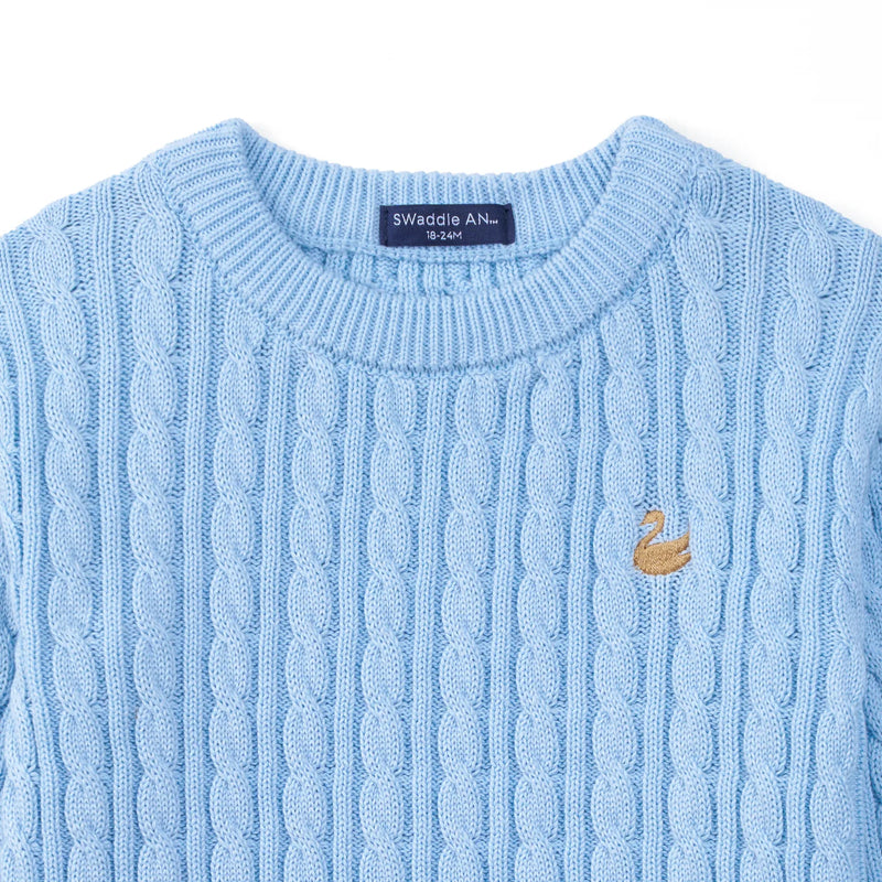 Close-up of navy size tag, ribbed collar, and gold embroidered swan on baby blue knit