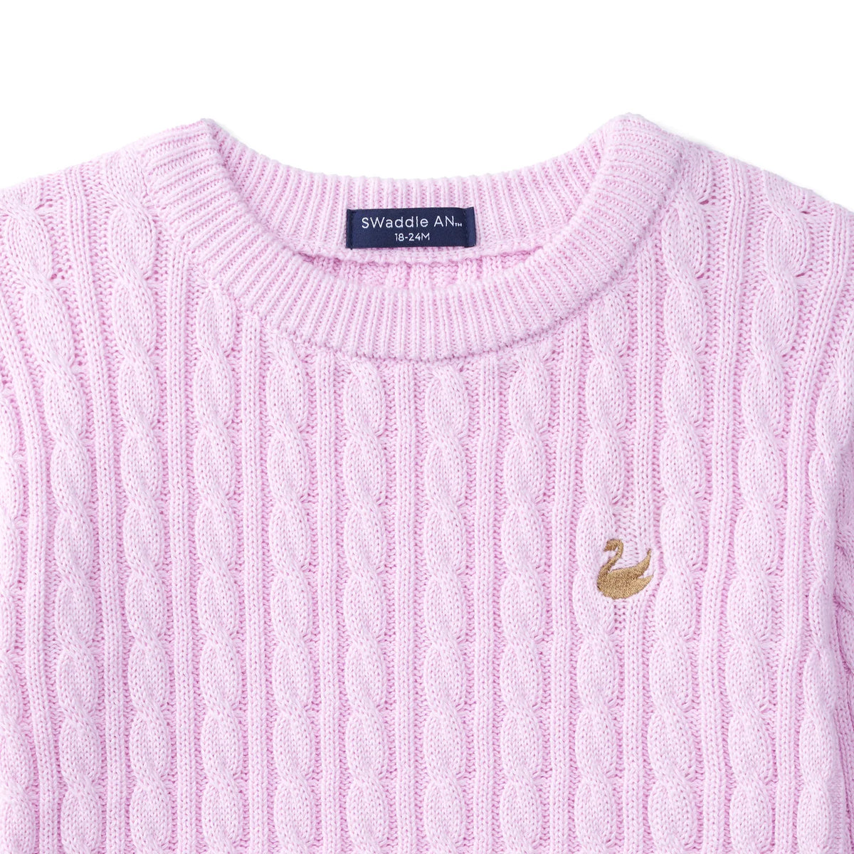 Close-up of lilac cable knit texture, blue neck label reading SWaddle AN, and gold swan embroidery