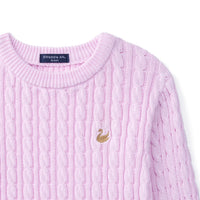 High-angle view of ribbed crew neck stitching, back collar tag, and gold swan emblem on textured knit