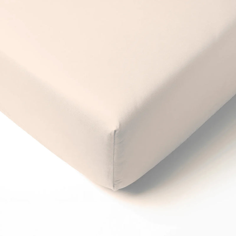 Sand-colored bamboo crib sheet corner fitted tightly on mattress showing smooth texture and elastic edge