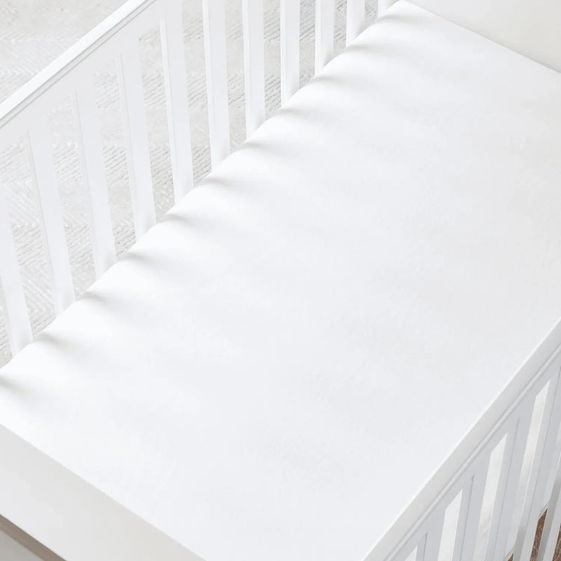 White fitted sheet on slatted crib mattress showing snug fit in nursery