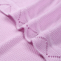 Close-up of intricate lace border detail on soft lilac cotton yarn texture