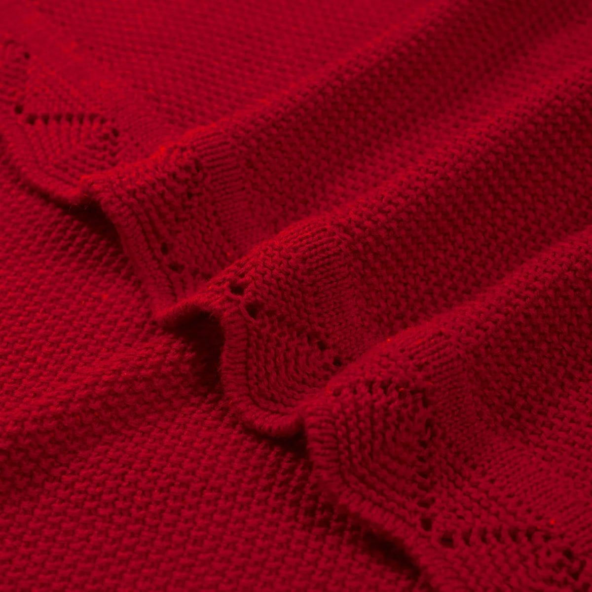 Close-up of red cotton fabric texture and delicate openwork lace pattern along scalloped border
