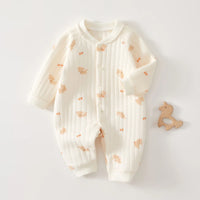 Cream quilted baby romper with teddy bear print, long sleeves, front buttons, and wooden teether for cozy warmth.