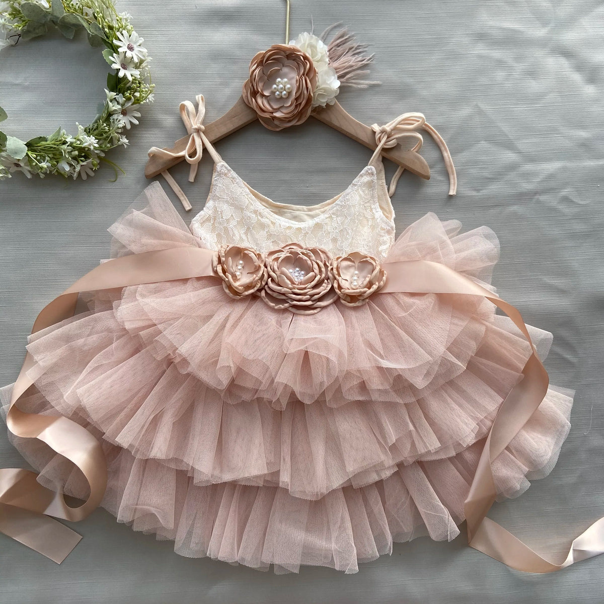 Cecilia tiered tulle dress with blush floral belt on hanger; lace bodice and layered tulle skirt.