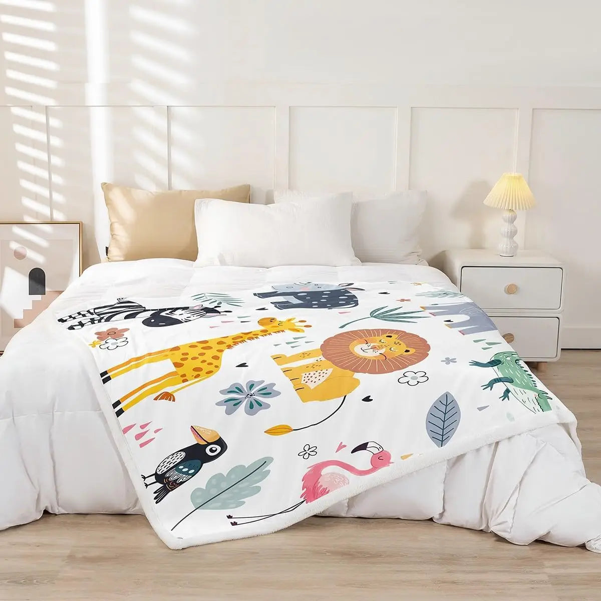 Jungle Rumble double-sided children's blanket with lion, giraffe, zebra, flamingo on a white bed.
