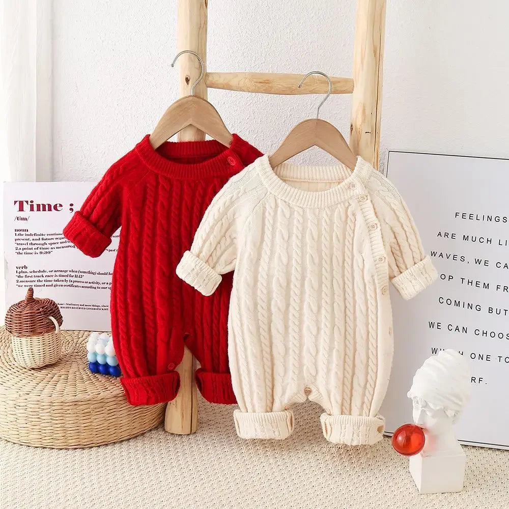 Two color options of the 'Cameron' Classic Cable Baby Knit Romper displayed on hangers, featuring azalea red and creamy beige designs.