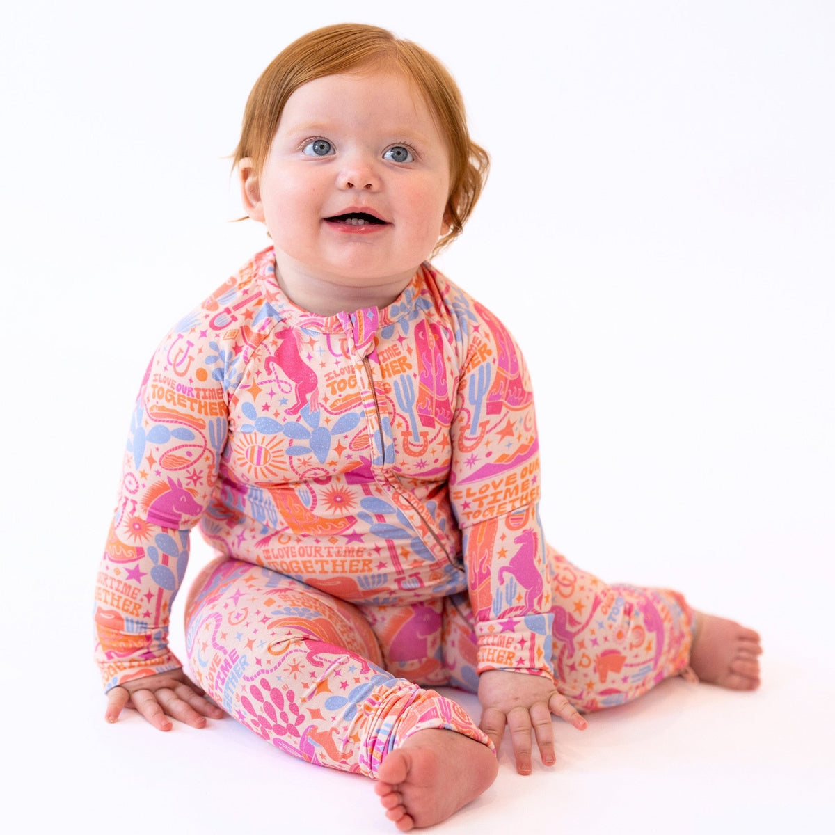 Baby wearing The Second-Skin Convertible Romper Saddle Up in a pink Saddle Up print; Raising Mama viscose from bamboo.