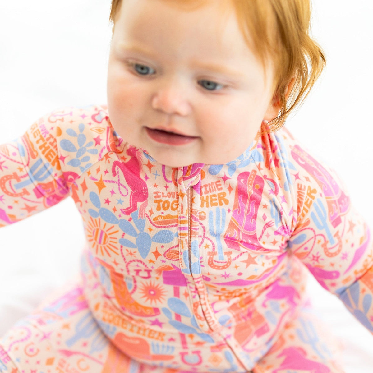 The Second-Skin Convertible Romper by Saddle Up: baby in colorful zippered romper with playful print