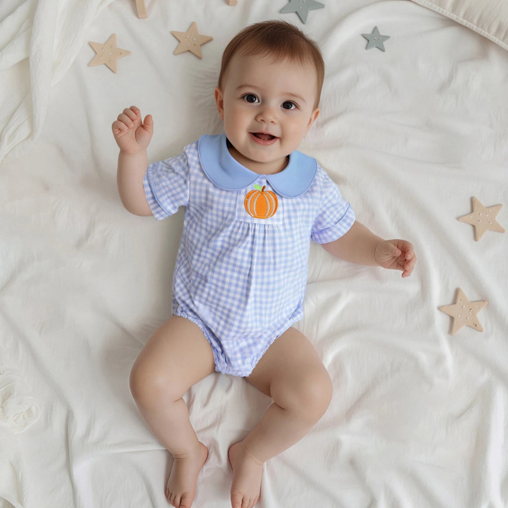 Happy baby wearing the "Pumpkin Folly" Embroidered Pumpkin Romper in a blue and white check pattern, showcasing a cute embroidered pumpkin.