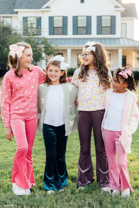 Four girls model a pink star print sweater, velvet flares, and daisy top.Perfect cozyKids winter wear.