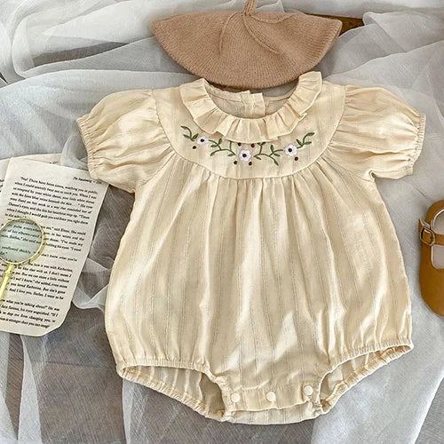 Spring Frills Baby Bubbles in light beige with embroidered flowers and a ruffled collar, perfect for sunny days.